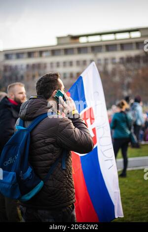Ragazzo che chiama il telefono cellulare con la bandiera slovacca nel suo Dimostrazione anti-governativa slovacca diretta contro le restrizioni del virus corona Foto Stock