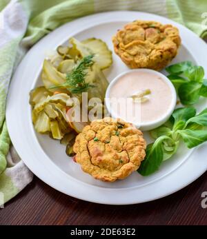 Primo piano su un antipasto a base di piante: Muffin vegetali vegani con salsa leggera di peperoncino-mayo e insalata di sottaceti di cetrioli, luce naturale Foto Stock
