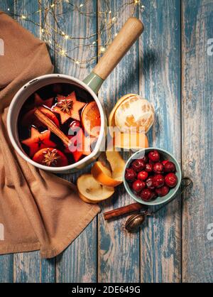 Tabella Still-life con pentola di VIN brulé con spezie, frutta, bastoncini di cannella, buccia d'arancia sullo sfondo rustico della superficie del tavolo. Natale e nuovo Foto Stock