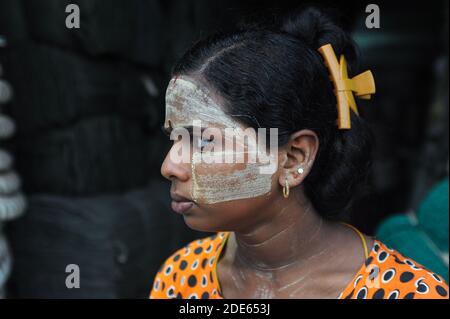 04.10.2013, Yangon, Myanmar, Asia - Ritratto di una giovane donna locale che ha applicato la pasta di Thanaka sulla sua faccia che è fatta dalla corteccia dell'albero di terra. Foto Stock