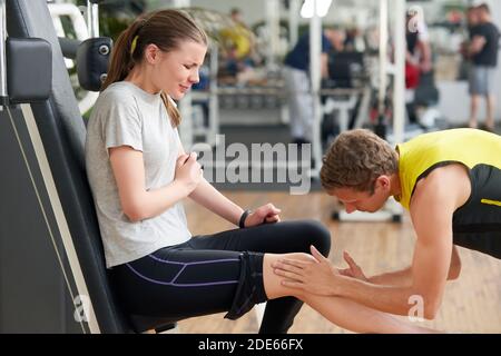 Giovane donna infelice con ginocchio ferito in palestra. Foto Stock