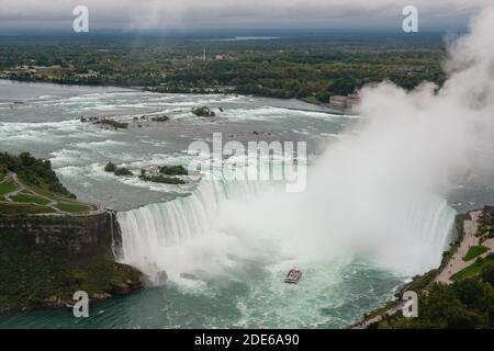 Vista panoramica delle Cascate del Niagara Tour in barca a vela nella cascata delle Cascate Horseshoe con nebbia d'acqua che scende verso il cielo, Ontario, Canada Foto Stock