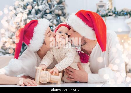 Felice famiglia sotto l'albero di Natale. Bambino ragazzo in cappello di Babbo Natale con regali sotto l'albero di Natale con molti regali delle scatole di regalo. Buone feste, anno nuovo Foto Stock