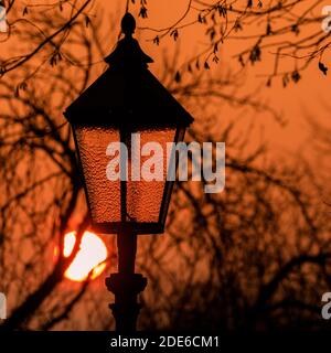 Xanten, NRW, Germania. 29 Nov 2020. Il sole tramonta dietro una vecchia lanterna di strada nella storica città di Xanten, sul fiume Reno, nel Nord Reno-Westfalia, Germania. Credit: Imageplotter/Alamy Live News Foto Stock