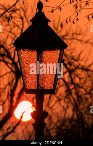 Xanten, NRW, Germania. 29 Nov 2020. Il sole tramonta dietro una vecchia lanterna di strada nella storica città di Xanten, sul fiume Reno, nel Nord Reno-Westfalia, Germania. Credit: Imageplotter/Alamy Live News Foto Stock