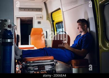 Giovane medico in una uniforme blu testando a qualcuno di notte. Foto Stock