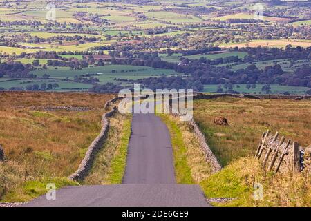 Vista che guarda lungo una strada di campagna vicino a Staimore con l'Eden Valley in lontananza, Cumbria, Inghilterra, Regno Unito. Foto Stock