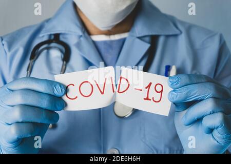 Il medico strappa il white paper che dice Covid-19. Concetto di epidemia di coronavirus. Foto Stock