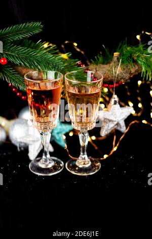 Capodanno e Natale decorazione. Bicchieri per champagne, giocattoli per l'albero di Natale stand sul tavolo di fronte al buio, bella bokeh sul backg Foto Stock