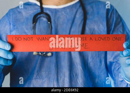 Il medico dà il messaggio di soggiorno a casa con carta rossa in mano. Foto Stock