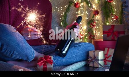 Natale in linea famiglia greetings.Woman che tiene sparkler e champagne nelle mani Augura agli amici e alla famiglia buon Natale e Felice anno nuovo tramite video Foto Stock