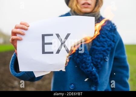 Primo piano su carta bianca con la parola stampata ex in mano femminile all'aperto, relazioni finite, divorzio, cuore rotto, avviare nuova vita Foto Stock