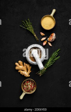 Composizione con miscela di peperoni, zenzero, aglio, timo e rosmarino su fondo scuro Foto Stock
