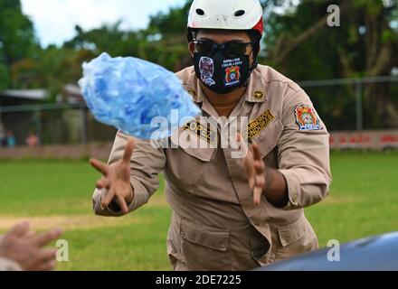 Base aerea di Soto Cano, Honduras. 28 Nov 2020. Un vigile del fuoco dell'Honduran cattura un sacco di ghiaccio scaricato da un elicottero Black Hawk dell'esercito degli Stati Uniti UH-60 per assistere nel periodo successivo all'uragano Iota 28 novembre 2020 a San Pedro Sula, Honduras. Tornando indietro gli uragani ETA e Iota hanno attraversato l'America Centrale distruggendo grandi tratti della costa e le strade delle inondazioni. Credito: Tsgt. Jael Laborn/US Air Force/Alamy Live News Foto Stock