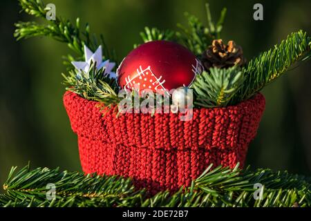 Una decorazione per Natale con un ramo di pino, cono di pino e pallina rossa isolati su sfondo verde Foto Stock