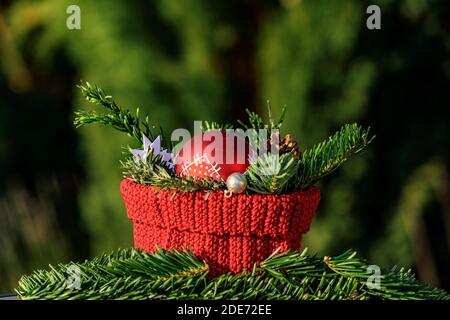 Decorazione di Natale con un cesto rosso, rami di abete e una palla rossa di albero di Natale su sfondo verde Foto Stock
