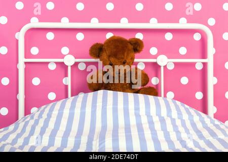 Camera da letto con girly rosa con orsacchiotto seduto sul letto Foto Stock