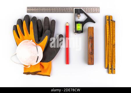 Guanti, metro a nastro e matita per lavori di carpenteria. Accessori per carpenteria utilizzati in officina. Sfondo chiaro. Foto Stock