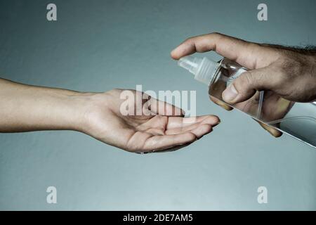 Uomo spruzzando disinfettante nella mano della donna. Covid-19, Coronavirus, epidemia di SARS-COV-2. 2019 - 2020 nuovo concetto e background di Coronavirus. Foto Stock