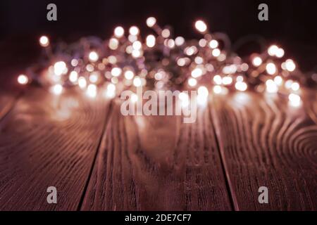 Luci di natale scintillanti su un tavolo di legno scuro. Decorazioni illuminanti con lampi a LED in un'oscurità. Natale e Capodanno. Spazio di copia. Foto Stock