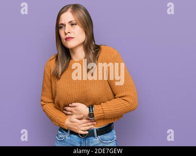 Bella donna caucasica che indossa abiti casual con la mano sullo stomaco perché indigestione, dolorosa malattia sensazione di malessere. Concetto di dolore. Foto Stock