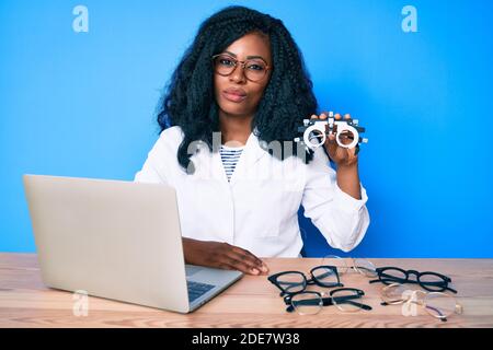 Bella donna africana che tiene occhiali di optometria pensare atteggiamento e sobrio espressione che si guarda sicuro di sé Foto Stock