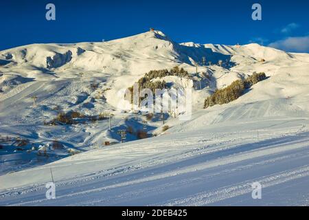 Splendido paesaggio invernale con popolare stazione sciistica al mattino. Piste da sci vuote e paesaggi spettacolari, la Toussuire, Francia, Europa Foto Stock