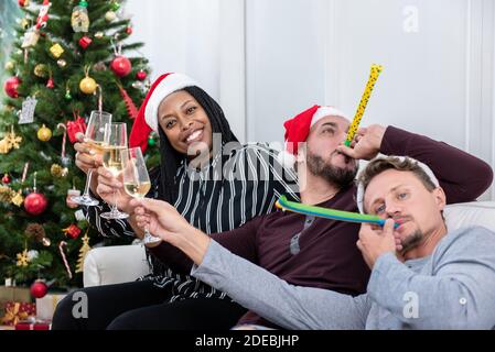 Donna afroamericana con gruppo di amici che festeggiano il Natale a. champagne da bere in casa Foto Stock