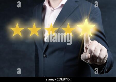Revisione e valutazione aumentare il concetto di azienda, mano di uomo d'affari toccando cinque stelle. Revisione, aumentare il rating o la classifica, uomo d'affari fare clic su cinque giallo Foto Stock