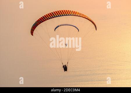 Paesaggio tramonto con parapendio nel cielo. Parapendio in tandem che sorvola il Mar Mediterraneo al tramonto. Foto Stock