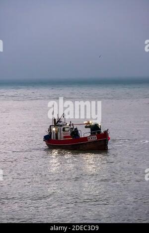 Hastings pesca barca che si stabilisce in mare all'alba per pescare nella Manica, Sussex orientale, Regno Unito Foto Stock