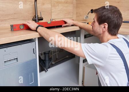 Idraulico maschile installa un lavandino in cucina Foto Stock