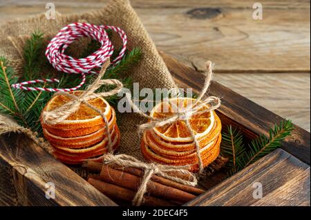 Composizione natalizia rustica con arance secche, bastoncini di cannella e rami di abete in una scatola di legno. Foto Stock