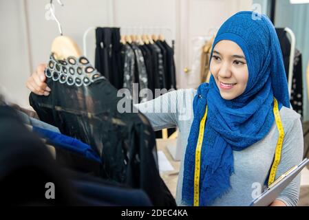 Donna musulmana asiatica designer come una start-up business proprietario di lavoro nel suo negozio su misura Foto Stock