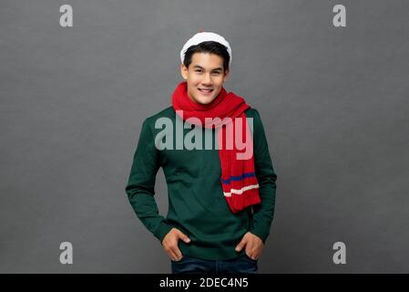Giovane bell'uomo asiatico che indossa colorful Natale rosso e verde abbigliamento in posa in studio con le mani in tasca Foto Stock