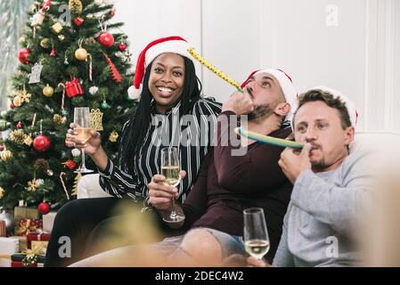 Donna afroamericana con gruppo di amici che festeggiano il Natale a. champagne da bere in casa Foto Stock