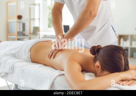 Paziente di donna mentente che ottiene il massaggio della parte posteriore dal chiropractor professionale o massaggiatore Foto Stock