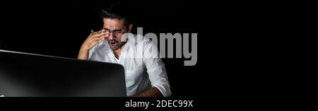 Stanco affaticato uomo d'affari asiatico sentirsi sonnolento e sbadigliare mentre lavoro turno di notte di fronte al computer, banner panoramico con spazio di copia Foto Stock