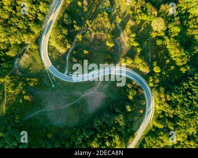Vista aerea sulla strada di montagna che attraversa il paesaggio forestale. Foto Stock