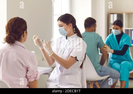 Infermieri qualificati che danno alle persone Covid-19 o vaccini influenzali durante la massa periodo di vaccinazione Foto Stock