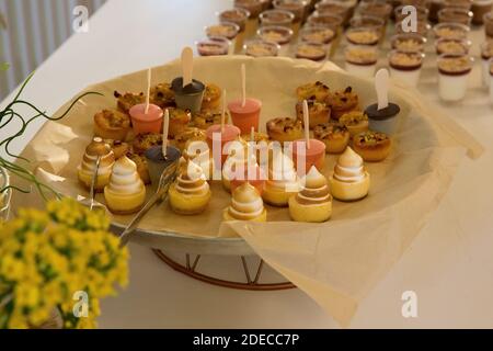 Un tavolo a buffet carico di cibo. Un piatto da dessert di tartelette dolci (piccole crostate con vari ripieni dolci) Foto Stock