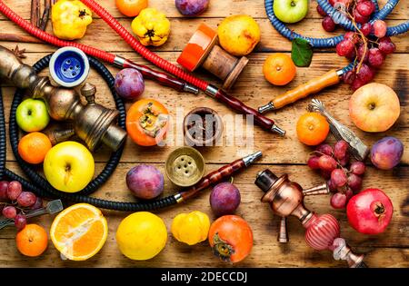 Hookah con mela, melograno, agrumi e uva aroma.Making hookah per fumare sopra sfondo di legno Foto Stock