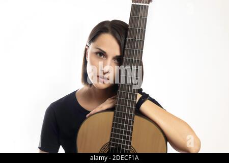 Ritratto di giovane bella brunetta con chitarra classica su sfondo bianco. Foto Stock