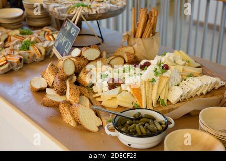 Assortimento di formaggi guarniti con uve intere e verdi un piatto di legno Foto Stock