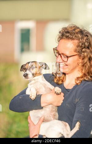 Amore per gli animali domestici. Jack Russell Terrier cane seduto tra le braccia della giovane donna. Foto Stock