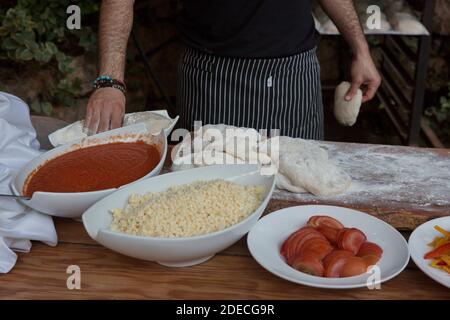 Preparazione e cottura di una focaccia pizza con purea di pomodoro e. formaggio Foto Stock