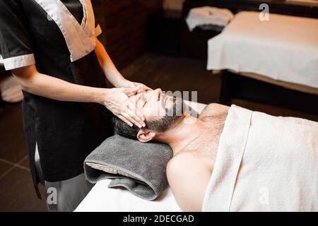Uomo con bearded che riceve un massaggio facciale, che si rilassa al salone Spa, primo piano Foto Stock