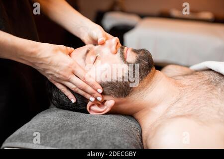 Uomo con bearded che riceve un massaggio facciale, che si rilassa al salone Spa, primo piano Foto Stock