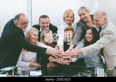 Gruppo di dipendenti che si uniscono ai loro palmi sopra la scrivania. Foto Stock