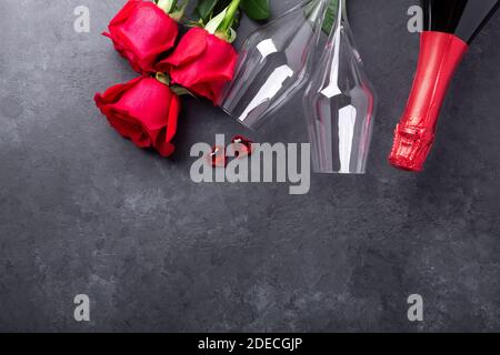 Biglietto d'auguri per San Valentino. Rose rosse, champagne, bicchieri su sfondo di pietra. Vista dall'alto - immagine Foto Stock